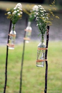Bottiglie di vetro legate ad un paletto usate come vasi